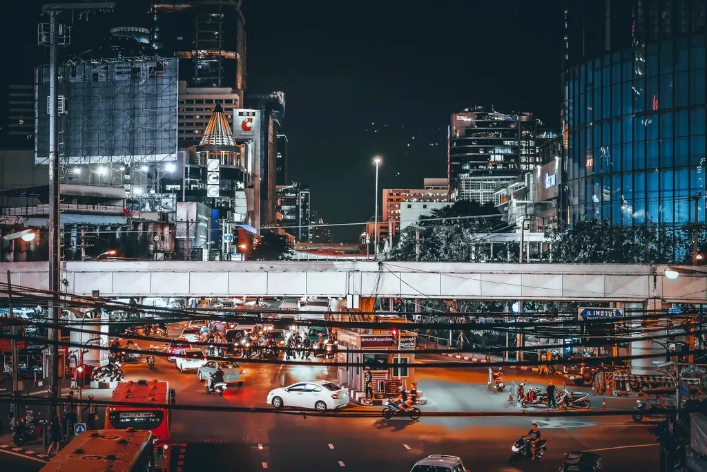 A busy Bangkok intersection at night under an elevated road